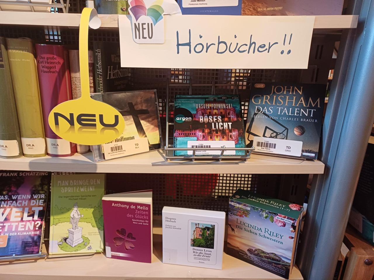 Auslage mit neuen Hörbüchern in der Bibliothek. Deutlich zu sehen: „Das Talent“ von John Grisham, „Böses Licht“ von Ursula Poznanski und „Die sieben Schwestern“ von Lucinda Riley.